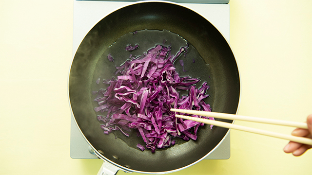 2. フライパンを強火にかけて、水を入れ、紫キャベツを加えて炒める。